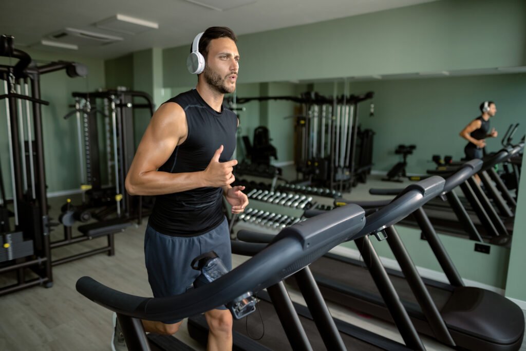 man working out on treadmill with gym equipment in background